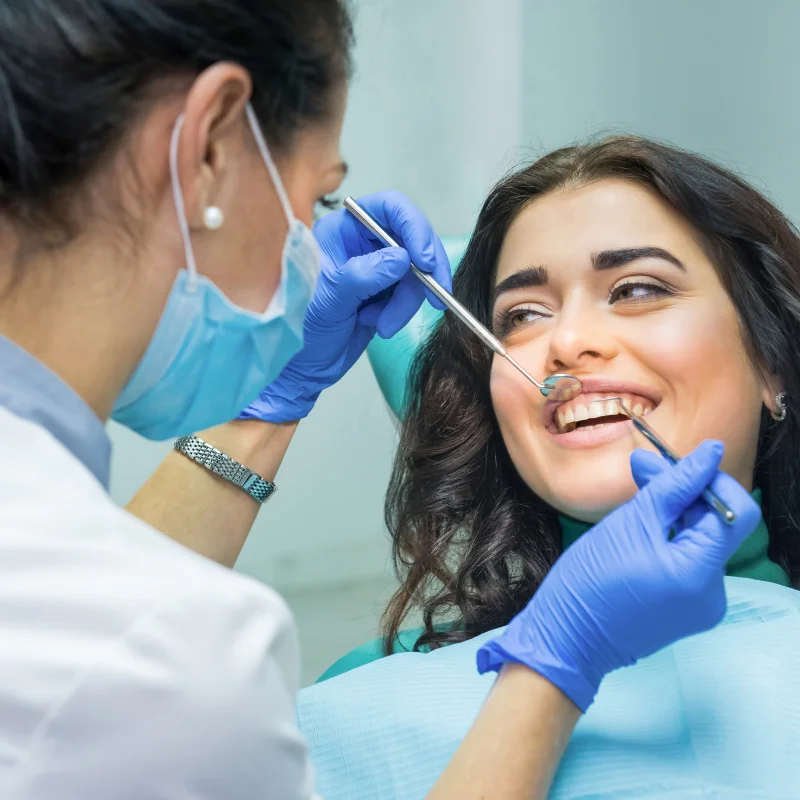 Dentist examining female patient's teeth during dental implant consultation