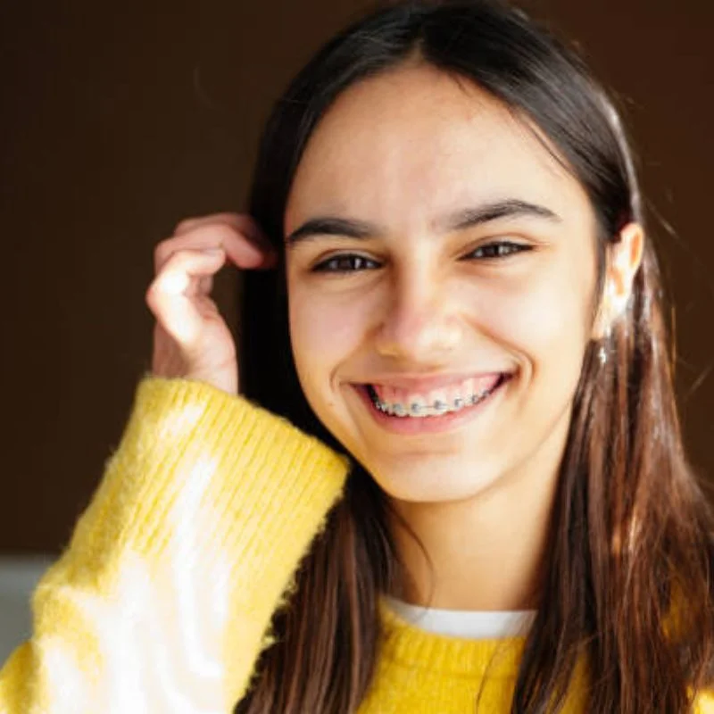Teenage girl smiling confidently while wearing orthodontic braces