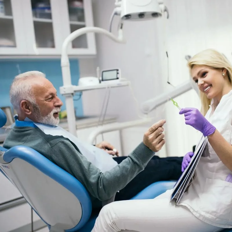Elderly male patient discussing denture options with dentist during consultation