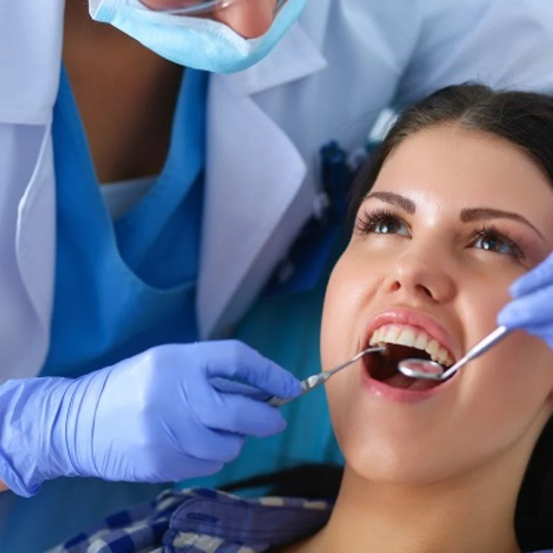 Dentist examining female patient's teeth during dental bridge consultation