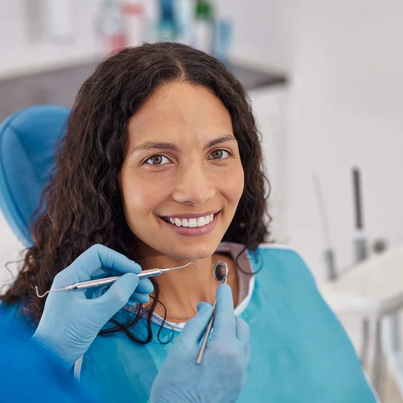 Female patient smiling in dental chair during dental restoration consultation with exam tools visible