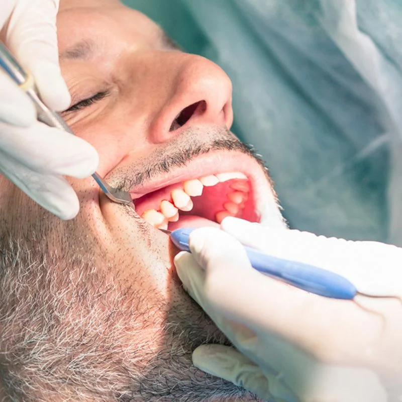 Dentist performing emergency dental exam on male patient using mirror and explorer tools