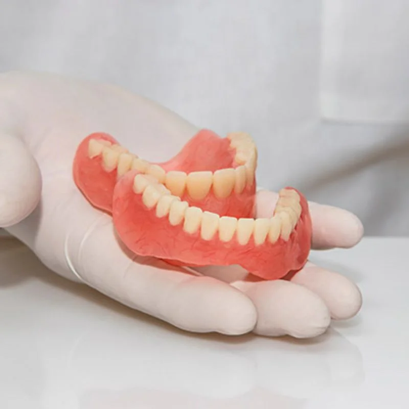 Dentist holding a full set of custom dentures in a gloved hand