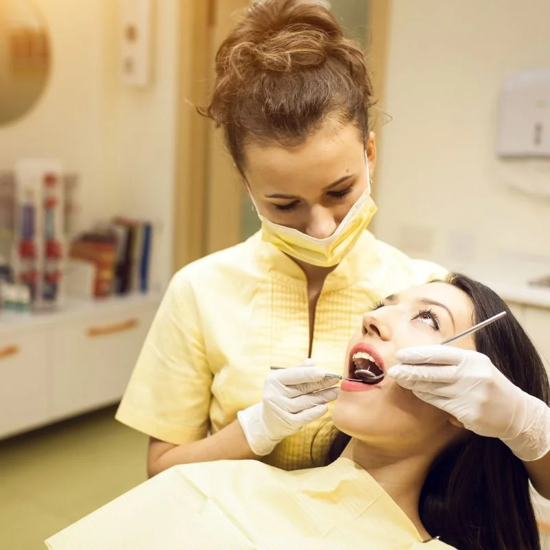 Dentist examining female patient's teeth during dental crown consultation