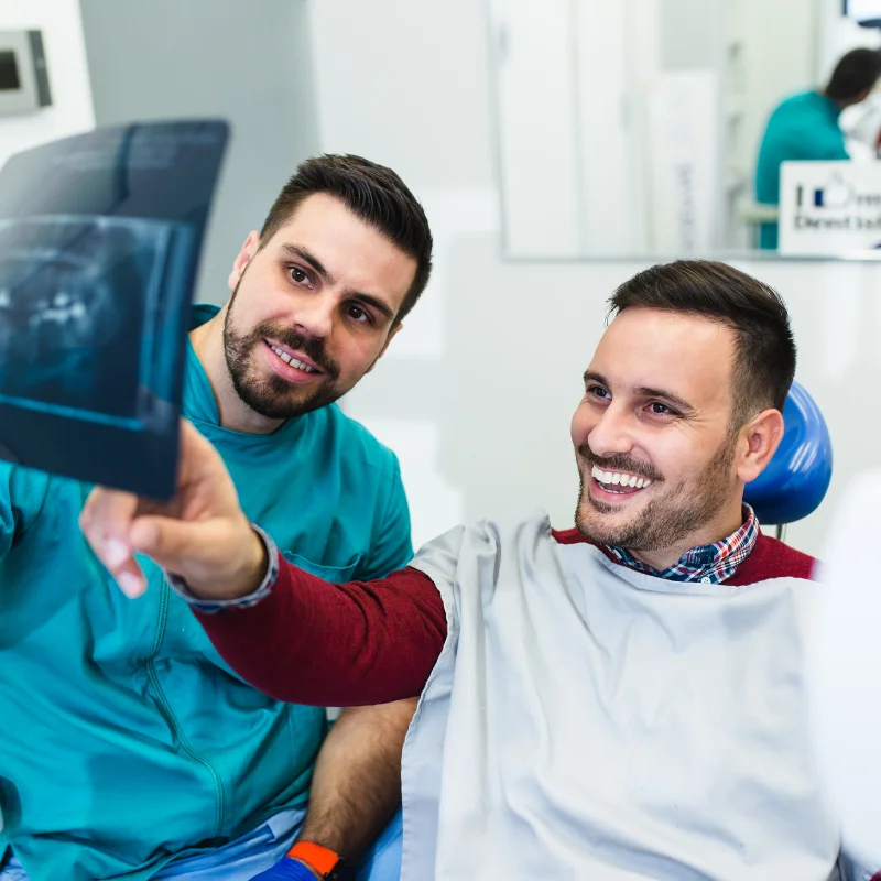 Dentist reviewing dental X-ray with male patient during Invisalign consultation