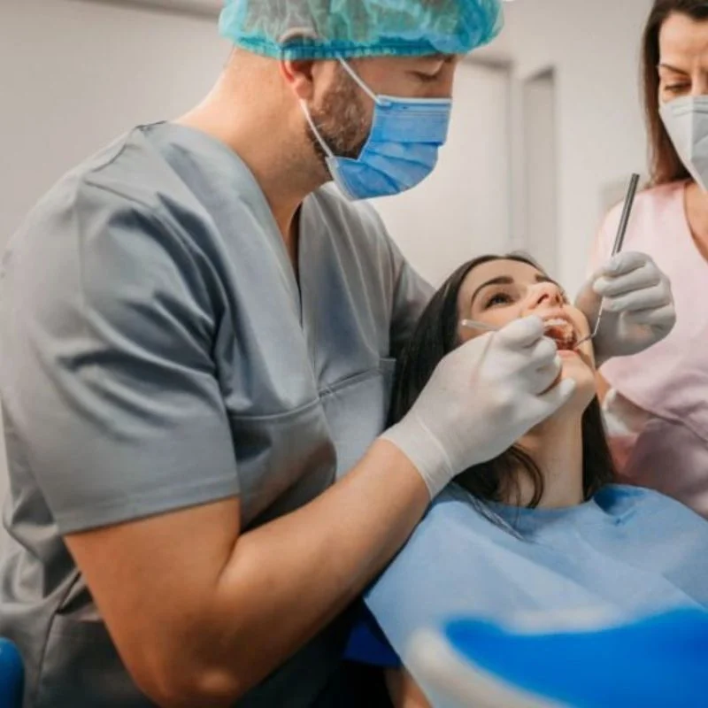 Dentist and dental assistant providing emergency dental treatment to female patient