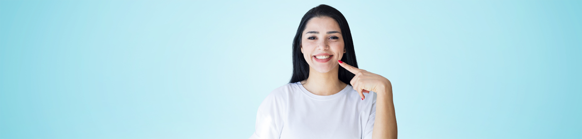 Dental restorations for repairing and enhancing teeth at Parkside Drive Dental Waterloo ON Female patient smiling and pointing at teeth, representing dental restorations at Parkside Drive Dental in Waterloo, ON